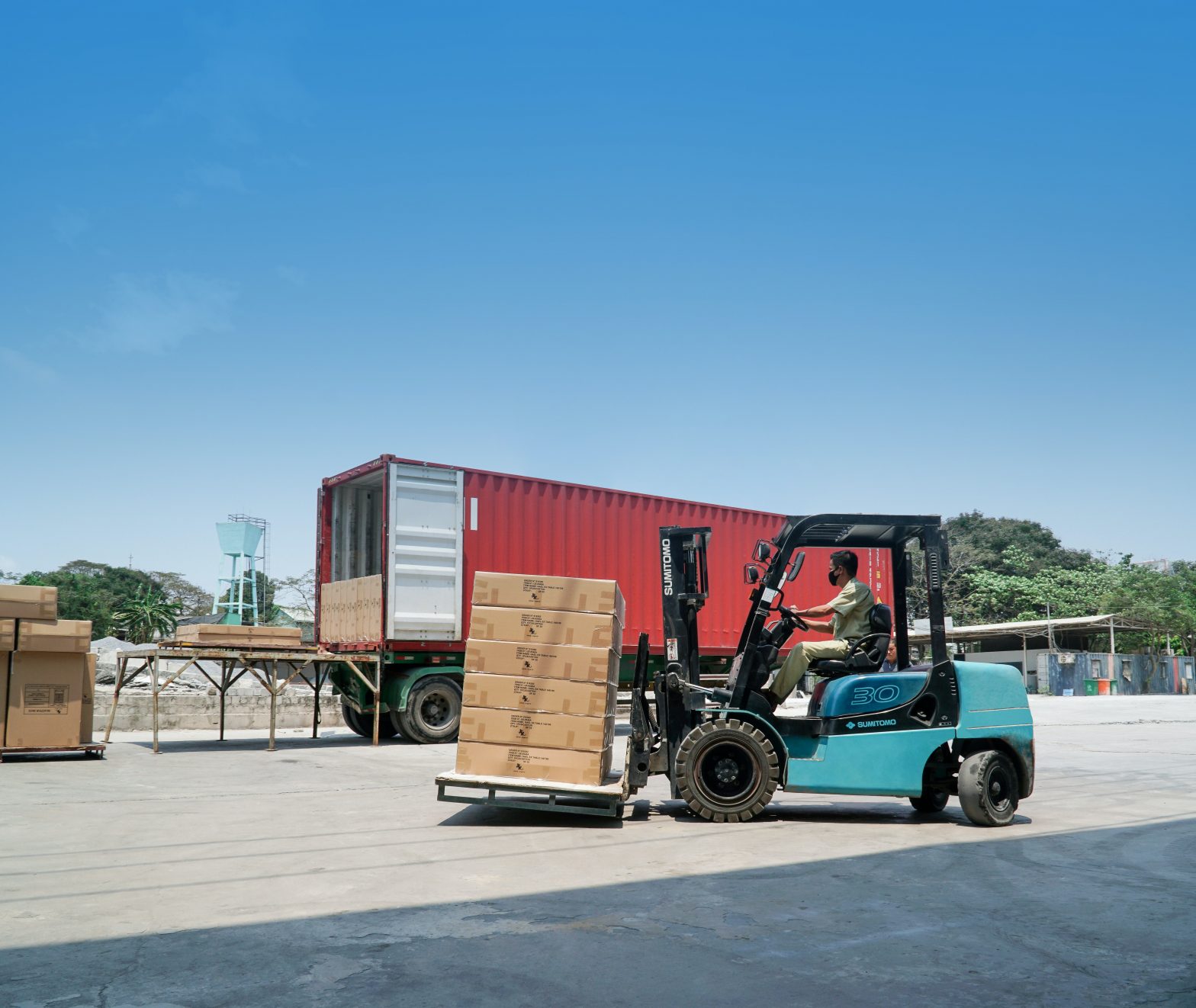 A truck is being loaded up with pallets by a forklift operator